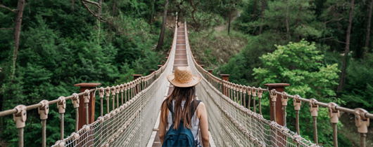 Compensation planning for 147 markets image of woman wearing backpack and hat walking across bridge in the woods